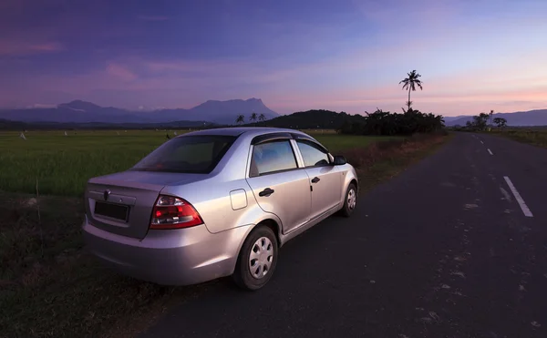 Car parked on roadside in a rural area at sunset — Stock Photo, Image