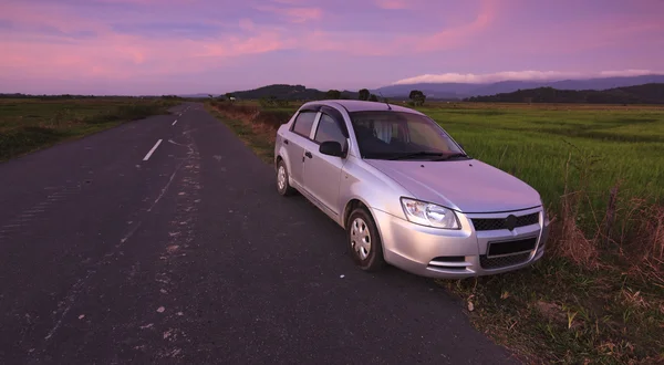 Car parked on roadside in a rural area at sunset — Stock Photo, Image