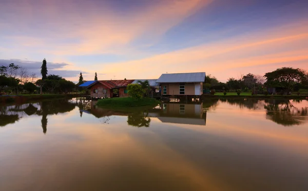 Heijastus puinen mökki ja värikäs auringonlasku Sabah, Borneo, Malesia — kuvapankkivalokuva