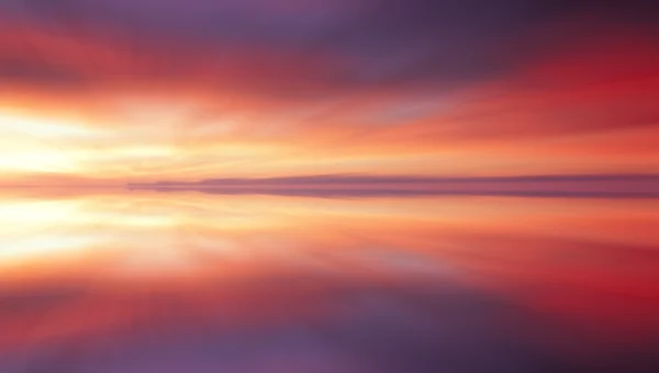 Weerspiegeling van kleurrijke zonsondergang wolken met lange blootstelling ingang, zoom wazig Stockfoto