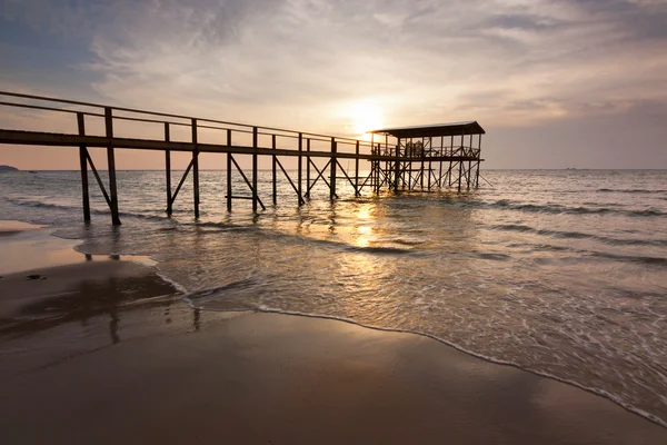 Puesta de sol con silueta de un embarcadero de madera en una playa en Sabah, Malasia, Borneo — Foto de Stock