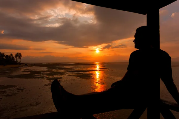 Silhueta de um homem relaxante ao pôr-do-sol — Fotografia de Stock