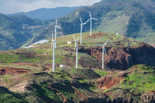 : East extremity of island Madiera are brightly shined by a sunset. Windmills on abrupt coast of Atlantic ocean. Red rocks and the dark blue sea — Stock Photo, Image