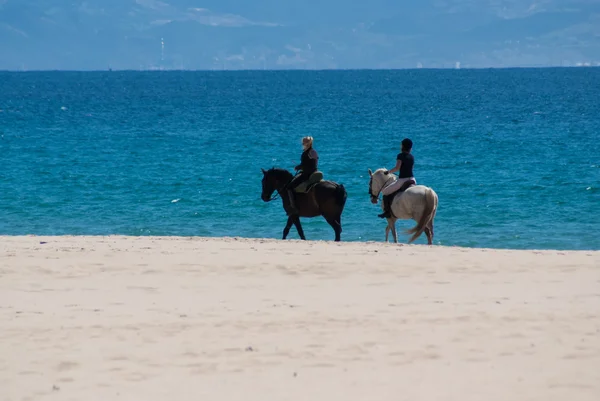 Dvě ženy jezdí na koních na pláži hihi — Stock fotografie