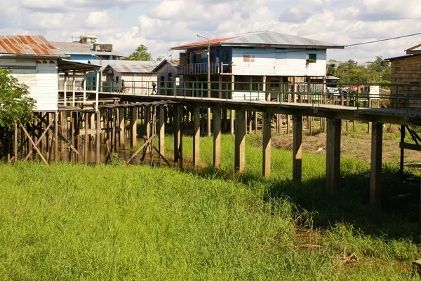 Hus på styltor stiga över det förorenade vattnet i islandia peru — Stockfoto