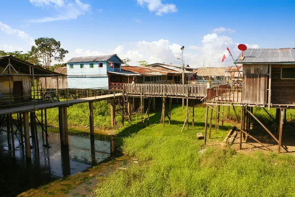 Häuser auf Stelzen ragen über das verschmutzte Wasser in Inselperu — Stockfoto