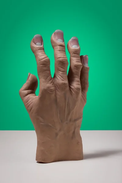 Huge fake hand on a green background — Stock Photo, Image