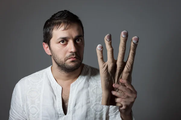 Joven barbudo sosteniendo una enorme mano simulada — Foto de Stock