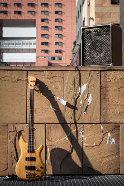 Bass guitar and amplifier against a wall — Stock Photo, Image