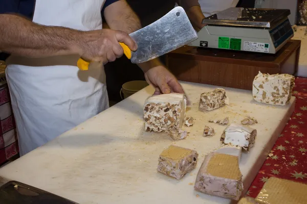 Man cutting a piece of torrone sweet at Golosaria 2013 in Milan, Italy — Stock Photo, Image