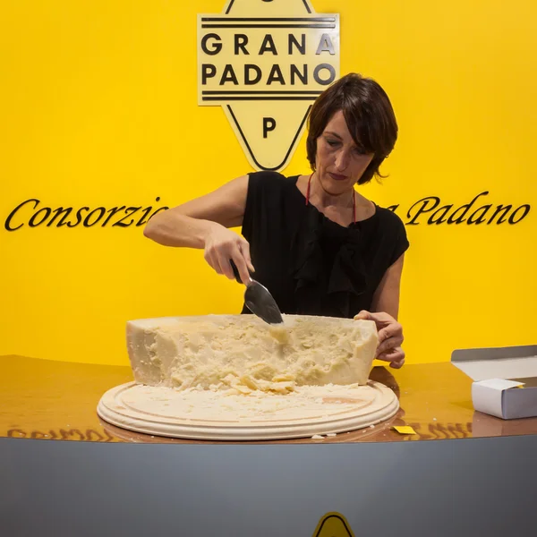 Woman cutting Grana Padano cheese into pieces at Golosaria 2013 in Milan, Italy — Stock Photo, Image