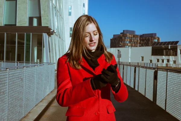 Mooi meisje met rode jas met behulp van telefoon — Stockfoto