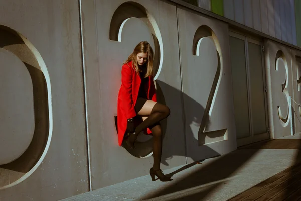 붉은 코트와 함께 포즈를 취하는 아름 다운 소녀 — 스톡 사진