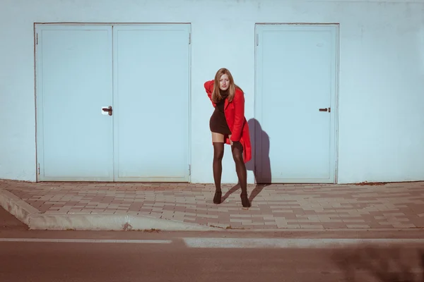 Beautiful girl posing with red coat — Stock Photo, Image