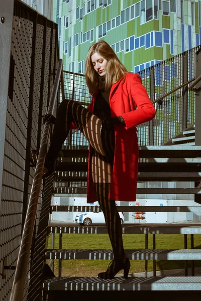 Красивая девушка позирует в красном пальто — стоковое фото