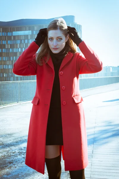 Schönes Mädchen posiert mit rotem Mantel — Stockfoto