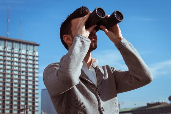 Portret van een knappe jonge man kijkend naar verrekijkers — Stockfoto