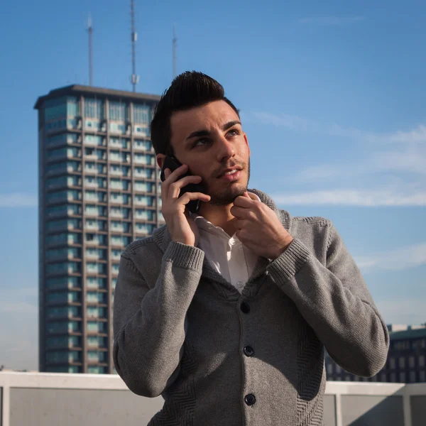 Portrett av en kjekk ung mann som snakker i telefonen – stockfoto