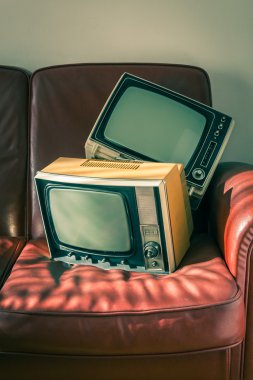 Kırmızı koltukta iki vintage televizyon