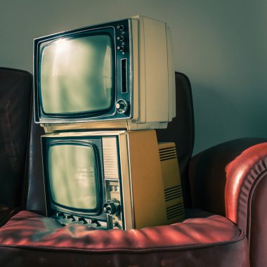 Kırmızı koltukta iki vintage televizyon