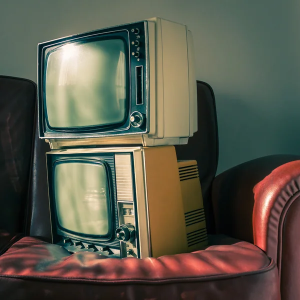 Two vintage televisions on red couch — Stock Photo, Image