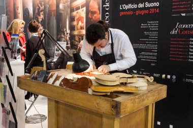 Luthier working on a violin at Bit 2014, international tourism exchange in Milan, Italy clipart