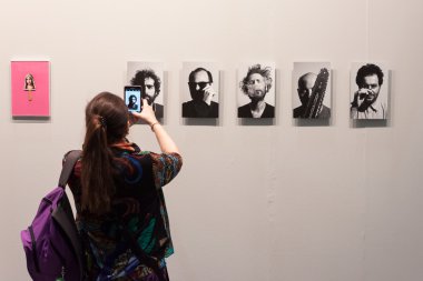 Woman taking a picture at Miart 2014 in Milan, Italy clipart