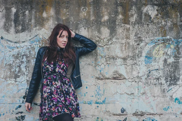 Menina bonita com cabelos longos encostados a uma parede de concreto — Fotografia de Stock