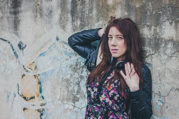 Pretty girl with long hair leaning against a concrete wall — Stock Photo, Image