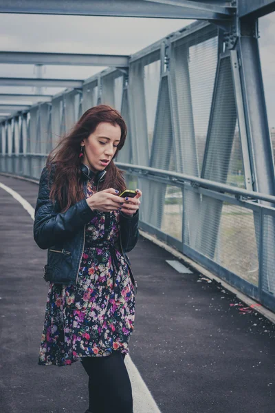 Chica bonita mensajes de texto en un puente — Foto de Stock