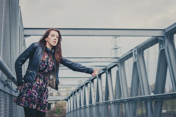 Pretty girl with long hair hitchhiking on a bridge — Stock Photo, Image