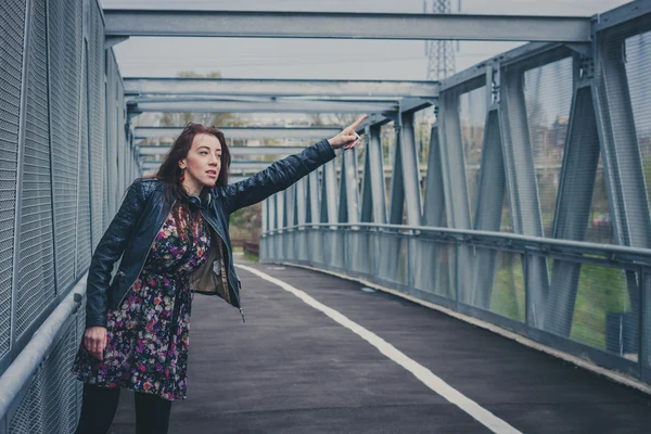 Menina bonita com cabelo comprido carona em uma ponte — Fotografia de Stock