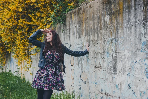 Menina bonita com cabelos longos encostados a uma parede de concreto — Fotografia de Stock