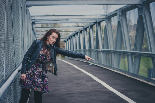 Pretty girl with long hair hitchhiking on a bridge — Stock Photo, Image