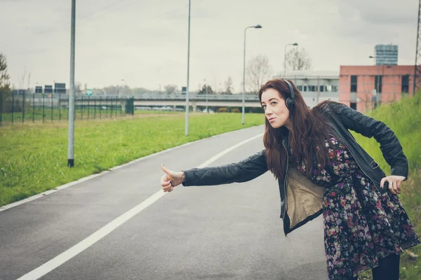 Pretty girl with long hair hitchhiking in the street — Stock Photo, Image