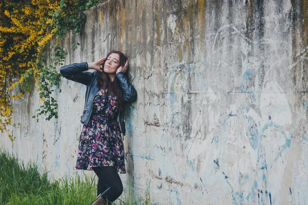 Söt flicka med långt hår lutad mot en betongvägg — Stockfoto