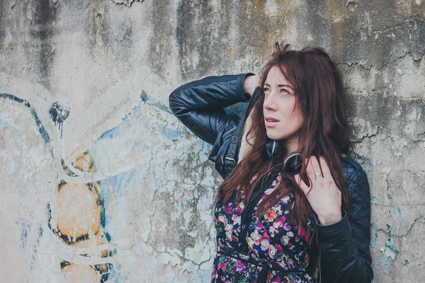 Pretty girl with long hair leaning against a concrete wall — Stock Photo, Image