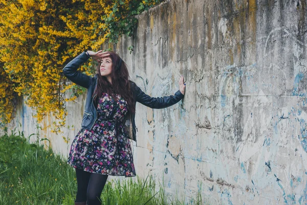 Bella ragazza con i capelli lunghi appoggiata a un muro di cemento — Foto Stock