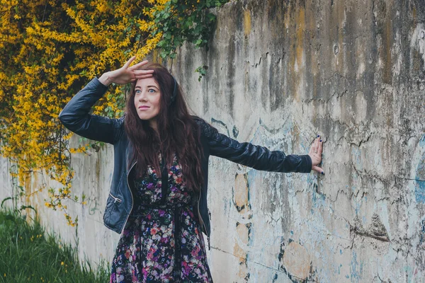 Pretty girl with long hair leaning against a concrete wall — Stock Photo, Image