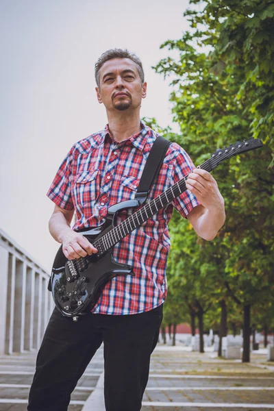 Man in short sleeve shirt playing electric guitar — Stock Photo, Image