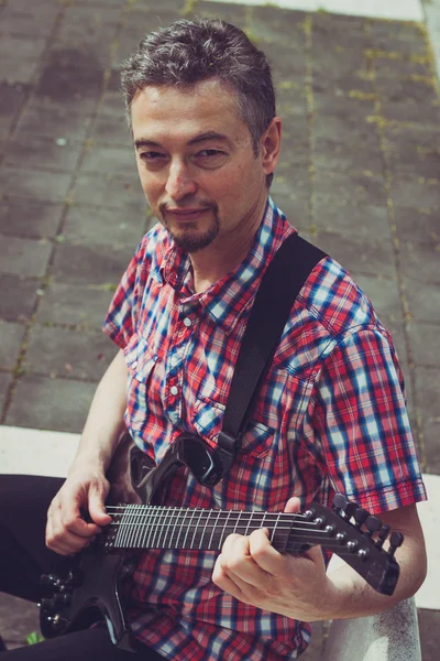 Man in short sleeve shirt playing electric guitar — Stock fotografie