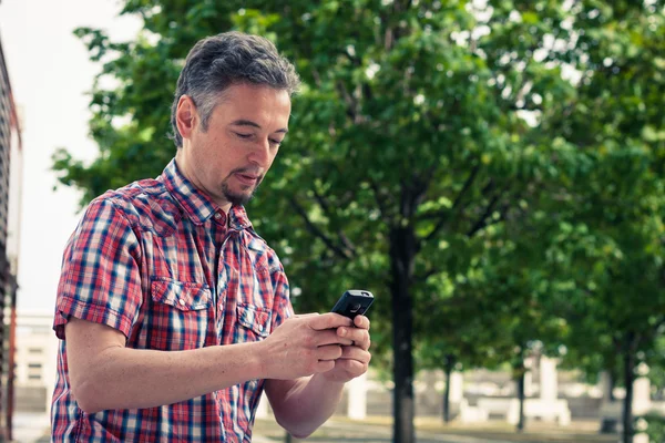 Bărbat în cămașă cu mânecă scurtă mesaje text la telefon — Fotografie, imagine de stoc