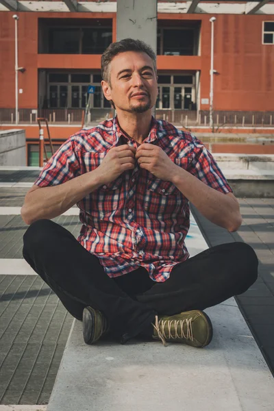 Мужчина в рубашке с коротким рукавом сидит снаружи — стоковое фото