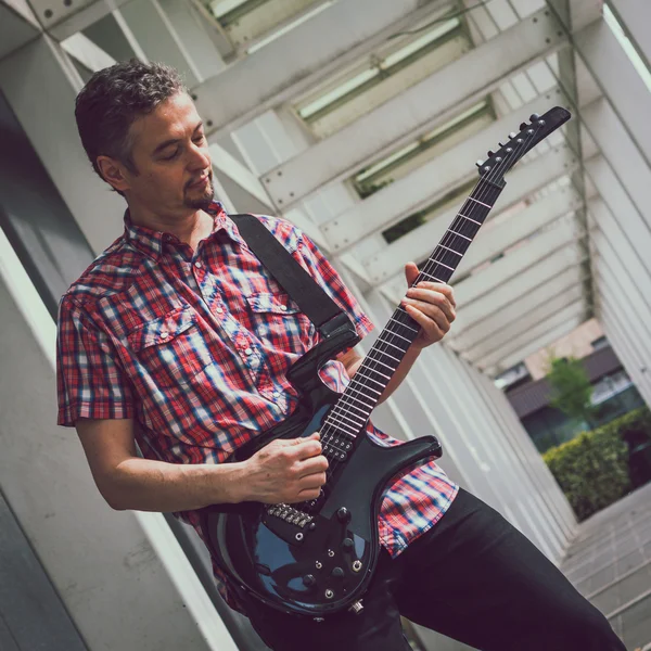 Man in short sleeve shirt playing electric guitar — Stock fotografie