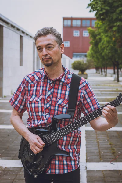 Man in short sleeve shirt playing electric guitar — Stock fotografie