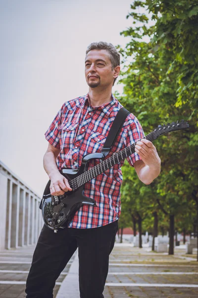 Man in short sleeve shirt playing electric guitar — Stock Photo, Image