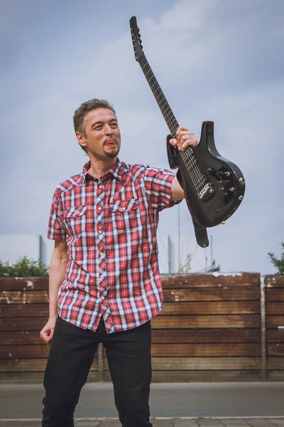 Homem de manga curta camisa segurando guitarra elétrica — Fotografia de Stock