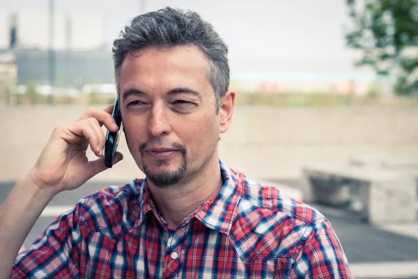 Мужчина в рубашке с коротким рукавом говорит по телефону — стоковое фото