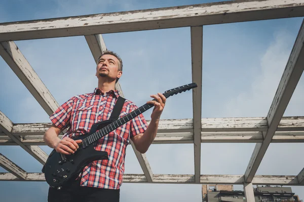 Man in short sleeve shirt playing electric guitar — Stock fotografie