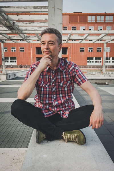 Man in short sleeve shirt sitting outdoor — Stock Photo, Image